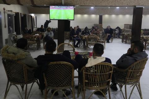 فلسطينيون يشاهدون مباراة تونس ضد الجزائر خلال نهائي كأس العرب على شاشة التلفزيون ، في دير البلح وسط قطاع غزة