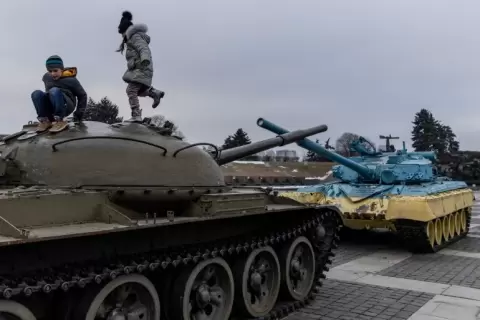 طفلان يلهوان على دبابة معروضة بكييف احتفالا "بيوم الوحدة" الذي أقرّه الرئيس ردا على التهديد الروسي بالغزو