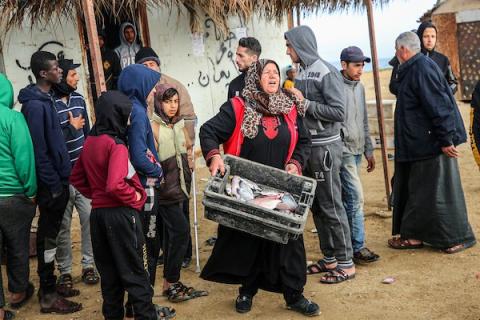المسنة الفلسطينية أم جميل الأقرع من دير البلح وسط قطاع غزة تشتري الأسماك من الحسبة لتبيعها في السوق، لتعيل أسرتهامع احتفال العالم بيوم المرأة العالمي.