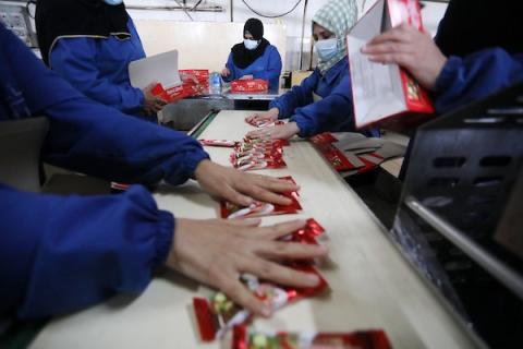 سيدات فلسطينيات يعملن داخل مصنع للمنتجات الغذائية في دير البلح وسط القطاع