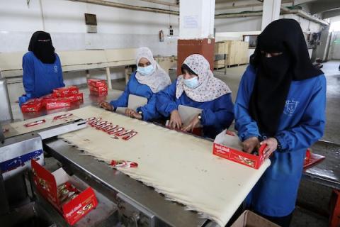 سيدات فلسطينيات يعملن داخل مصنع للمنتجات الغذائية في دير البلح وسط القطاع