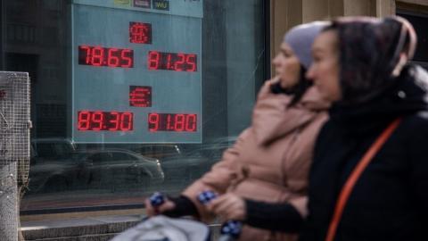 سيدات يسيرون أمام لوحة تعرض أسعار صرف عملات الدولار الأميركي واليورو مقابل الروبل الروسي في موسكو. 22/02/2022. (أ ف ب)
