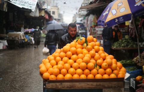 فلسطينيون يسيرون في أحد الشوارع خلال يوم ممطر في مدينة نابلس بالضفة الغربية
