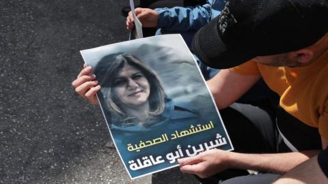 فلسطيني يحمل ملصقًا للشهيدة شيرين أبو عاقلة في مدينة الخليل. (أ ف ب).jpeg