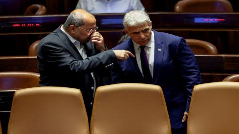 عضو الكنيست ورئيس القائمة العربية المشتركة أحمد الطيبي يتحدث إلى وزير الخارجية الإسرائيلي يائير لابيد في الكنيست، 22 حزيران/يونيو 2022. (رويترز)