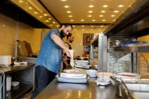 اللاجئ السوري أنس قاطرجي يعمل في مطعمه الخاص في غزة يوم 16 يونيو حزيران 2022. تصوير: محمد سالم - رويترز