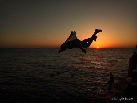 فلسطينيون يمارسون القفز داخل مياه البحر من أعلى حجارة ميناء خان يونس جنوبي قطاع غزة.jpg