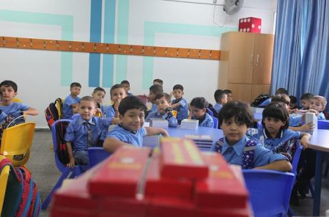 طلاب فلسطينيون يستلمون القرطاسية المدرسية في اليوم الأول من العام الدراسي الجديد في مدرسة تابعة لوكالة الغوث في مدينة غزة