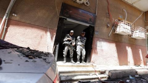 رجلا أمن يقفان في مكان اندلاع حريق في كنيسة أبو سيفين في الجيزة بمصر. 14/08/2022. (محمد عبد الغني/ رويترز)