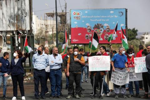 متظاهرون يحملون الأعلام الفلسطينية ويحرقون الإطارات على حاجز حوارة احتجاجا على استمرار الحصار الإسرائيلي على مدينة نابلس