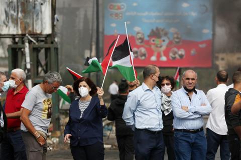 متظاهرون يحملون الأعلام الفلسطينية ويحرقون الإطارات على حاجز حوارة احتجاجا على استمرار الحصار الإسرائيلي على مدينة نابلس