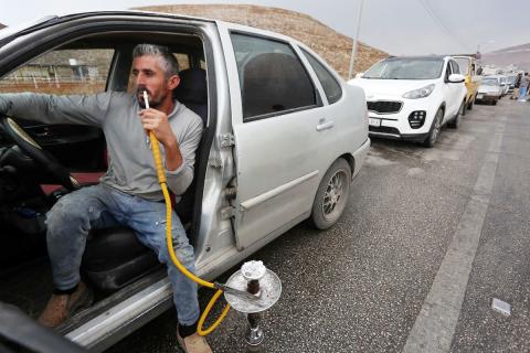 سائق سيارة فلسطيني يدخن النرجيلة في انتظار عبور حاجز تفتيش إسرائيلي بين مدينة نابلس وقرية بيت فوريك