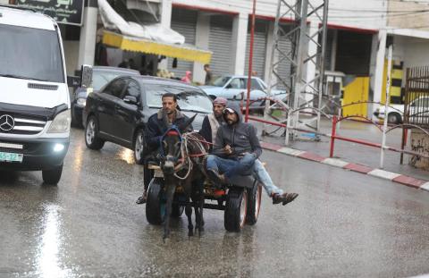 فلسطينيون يسيرون في شارع غمرته مياه الأمطار في دير البلح وسط قطاع غزة 4.jpg