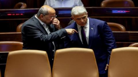عضو الكنيست ورئيس القائمة العربية المشتركة أحمد الطيبي يتحدث إلى وزير الخارجية الإسرائيلي يائير لابيد في الكنيست، 22 حزيران/يونيو 2022. (رويترز)