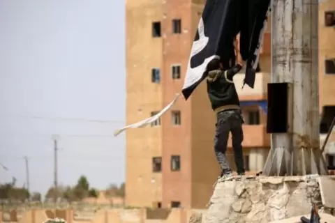 مقاتل كردي يزيل راية لتنظيم الدولة الإسلامية في مدينة الطبقة السورية في في 30 نيسان/أبريل 2017 afp