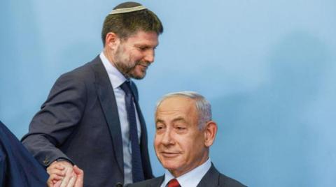 نتنياهو جالساً يصافح وزير المالية بتسلئيل سموتريتش (أ.ف.ب).jpg