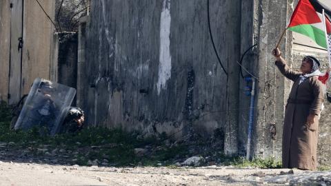 فلسطيني يلوّح بالعلم الوطني خلال مواجهات مع قوات الاحتلال الإسرائيلي في قرية كفر قدوم، 17 شباط/فبراير 2023. (أ ف ب)