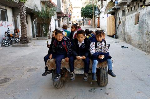 رجل فلسطيني يدعي لؤي أبو سحلول يوفر لبعض الطلاب رحلة بواسطة عربة بحمار إلى المدرسة في خان يونس جنوب قطاع غزة يوم 27 فبراير شباط 2023. تصوير: إبراهيم أبو مصطفى - رويترز.