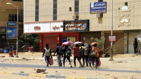 أشخاص يحملون أمتعتهم يسيرون على طول أحد شوارع الخرطوم. 16 نيسان/ أبريل 2023. (أ ف ب)