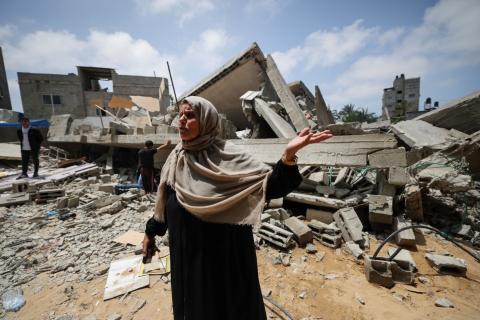 صورة التقطت في 15 أيا/مايو 2023 في بيت لاهيا وتظهر فيها الفلسطينية نجاح نبهان (56 عاما) وهي تتحدث وتشير إلى أنقاض المبنى السكني الذي كانت تقطنه هي وعائلتها قبل أن تقصفه إسرائيل  - محمود الهمص / ا ف ب