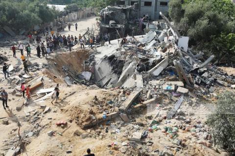 مواطنون يتفقدون آثار الدمار الذي خلفته غارة جوية على بيت لاهيا شمال غزة.jpeg