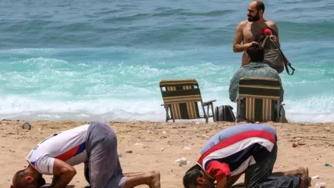 يؤديان الصلاة على شاطئ عام في صيدا احتجاجا على تحرّك داعم للباس السباحة في 21 أيار/مايو 2023 - محمود زيات / ا ف ب