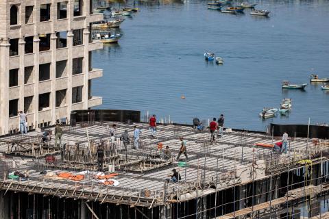 عمال بناء يضعون الأنابيب والشبكات الفولاذية لطابق في مبنى يطل على ميناء  24 مايو  (أ.ف.ب).jpeg