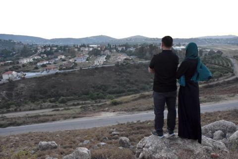 مواطنان لبنانيان في بلدة كفركلا الحدودية ينظران إلى «المِطلة» في إسرائيل على الجانب الآخر من الحدود (إ.ب.أ).jpeg