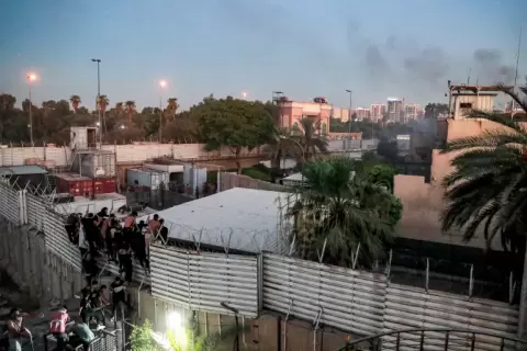 محتجون عراقيون يتسورون جدارا في السفارة السويدية ببغداد (الفرنسية).webp