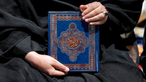 نسخة من القرآن الكريم يحملها متظاهر خلال تجمع حاشد في بغداد للتنديد بحرق المصحف الشريف في السويد. 21/07/2023. (أ ف ب)
