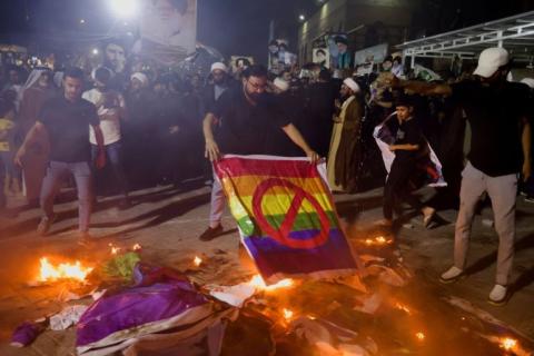 متظاهرون في بغداد يحرقون راية المثليين خلال احتجاجات على حرق المصحف في السويد (رويترز).jpg