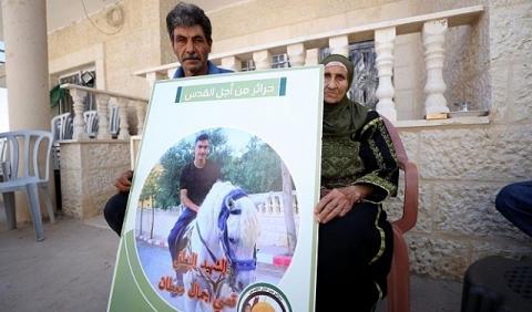 والدا الشهيد قصي معطان يحملان صورته، أول من أمس (Getty Images(.jpg