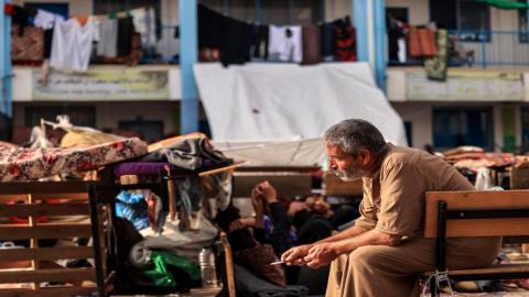 نازح فلسطيني ينفث دخان سيجارته في ساحة مدرسة تتبع لوكالة (الأونروا) في خان يونس في جنوب قطاع غزة، 25 تشرين الأول/ أكتوبر 2023. (أ ف ب)