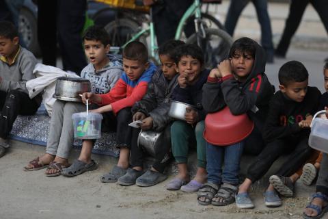 يقوم النازحون الفلسطينيون بجمع الطعام الذي تبرعت به إحدى الجمعيات الخيرية قبل وجبة الإفطار، في اليوم الرابع عشر من شهر رمضان المبارك، في دير البلح وسط قطاع غزة، في مارس 24 فبراير 2024. تصوير: عمر اشتيوي