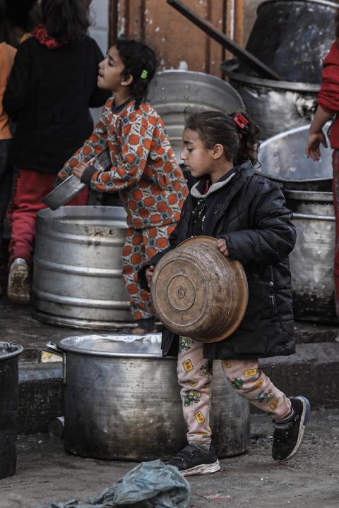 أطفال فلسطينيون يحاولون الحصول على بعض المواد الغذائية من إحدى الدور الخيرية في دير البلح وسط قطاع غزة. تصوير: عمر اشتيوي