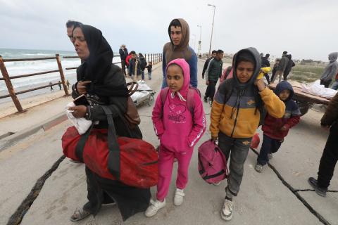 النازحون الفلسطينيون الفارون من المنطقة المحيطة بمستشفى الشفاء بمدينة غزة يصلون عبر الطريق الساحلي السريع إلى مخيم النصيرات للاجئين وسط قطاع غزة في 18 مارس 2024. تصوير: نعمان عمر