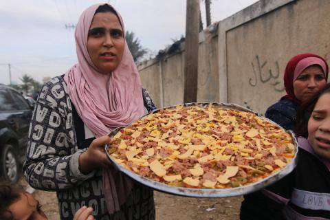 فلسطينيون يقومون بإعداد وجبة الإفطار خلال اليوم الحادي عشر من الصيام خلال شهر رمضان المبارك، في ملجأ للنازحين في دير البلح في وسط قطاع غزة، في 21 مارس 2024 . تصوير :علي حمد