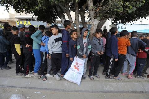 نازحون فلسطينيون يتجمعون لتلقي الطعام الذي تبرعت به مؤسسة خيرية قبل وجبة الإفطار، في اليوم الثالث من شهر رمضان المبارك، في دير البلح في وسط قطاع غزة في 13 مارس 2024 - بواسطة: عمر اشتيوي