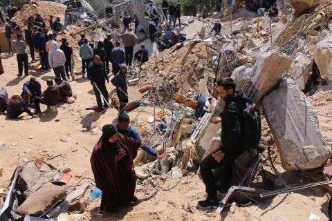فلسطينيون يتفقدون الأضرار التي لحقت بمبنى بعد القصف الإسرائيلي خلال الليل في دير البلح، قطاع غزة، في 25 مارس 2024. تصوير سعيد جرس