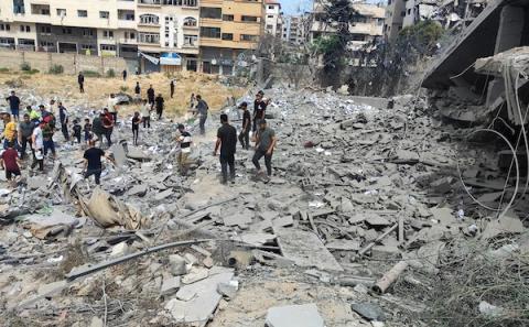 السكان الفلسطينيون الذين يعيشون في المنطقة يتفقدون المنزل المدمر بين الأنقاض بعد هجوم إسرائيلي على منزل في مدينة غزة، في 26 أبريل 2024. تصوير :خالد داود