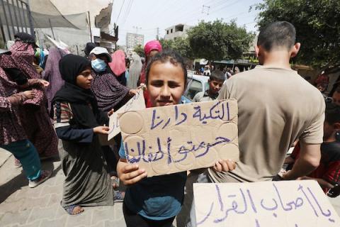 فلسطينيون يحملون أواني طعام فارغة أثناء مشاركتهم في تظاهرة للمطالبة بتوفير غاز الطهي للتكية الخيرية التي تقدم لهم الطعام يوميًا مجانًا، في دير البلح وسط قطاع غزة، 25 أبريل 2024. تصوير عمر: اشتياوي