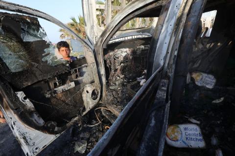فلسطينيون يتفقدون المركبات المتضررة بشدة بعد الهجمات الإسرائيلية التي استهدفت المسؤولين العاملين في منظمة المساعدة التطوعية الدولية