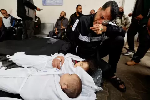 فلسطيني يبكي طفليه اللذين استشهدا مطلع الشهر الجاري جراء غارة إسرائيلية على رفح جنوبي قطاع غزة (رويترز).webp