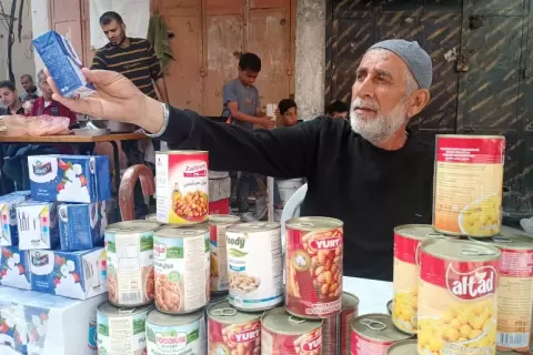 التاجر محمد الزايغ ينسب الفضل بتوفر السلع وانخفاض أسعارها إلى رجال تأمين المساعدات (الجزيرة).webp
