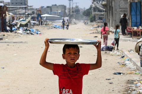 طفل فلسطيني يحمل فوق رأسه صينية تحتوي الخبز في قطاع غزة (أ.ف.ب)