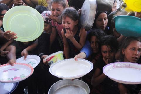 أطفال فلسطينيون يتجمعون لتلقي الطعام من مؤسسة خيرية وسط استمرار الحرب في قطاع غزة (رويترز)