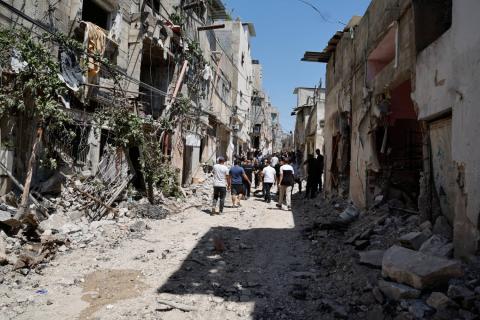 فلسطينيون يسيرون بين الأنقاض في أعقاب غارة إسرائيلية على طولكرم بالضفة الغربية (رويترز)