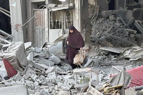 فلسطينية تخطو فوق أنقاض منزل دمرته الغارات الإسرائيلية