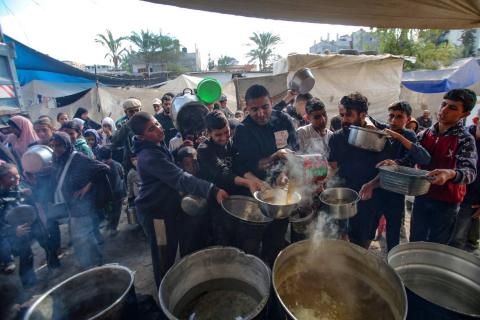 نازحون يتجمعون لتلقي وجبة ساخنة في مخيم البريج للاجئين في وسط قطاع غزة السبت (أ.ف.ب).jpeg