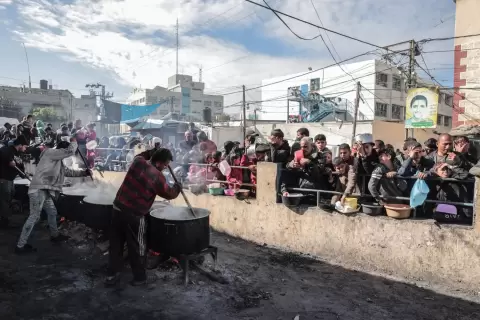 فلسطينيون ينتظرون الحصول على الطعام عند نقطة تبرع في مخيم للاجئين.webp